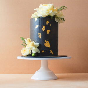 Large black icing cake with gold flakes and white flowers