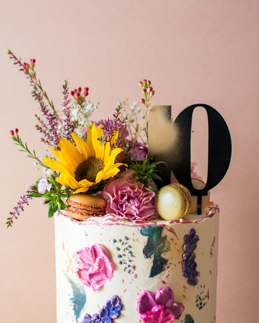 close up of a buttercream cake and macaroons, sunflowers and a topper