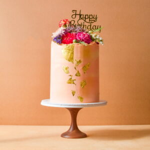 Large pink cake with gold flakes and flowers
