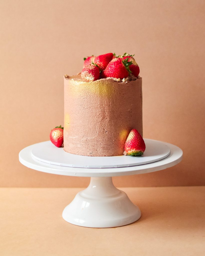 Chocolate and strawberry cake with gold spray painted on the sides