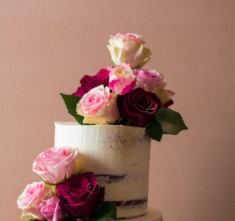 Close up of semi-naked wedding cake with roses
