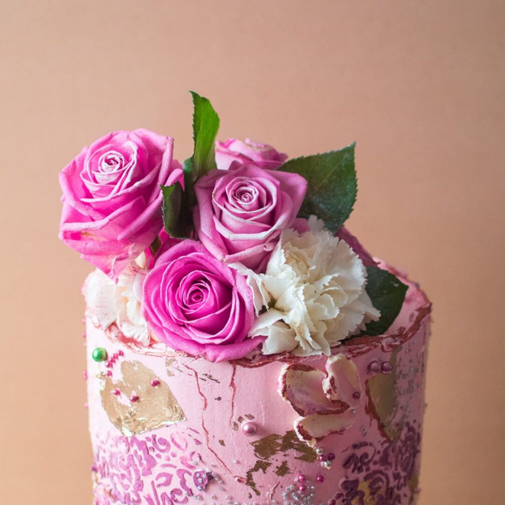 Close up of a pink cake with pink roses on top