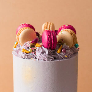 Close up of a cake with macarons and sprinkles on top