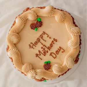 Elegant vintage cake with piped swirls and “Happy Mother’s Day” message in neutral tones