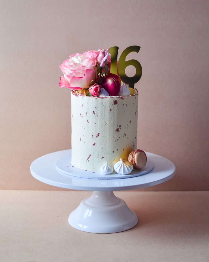 a rose gold 16th birthday cake with rustic look and flower on top