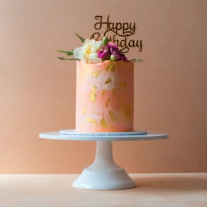 Light pink cake with flowers and a happy birthday topper
