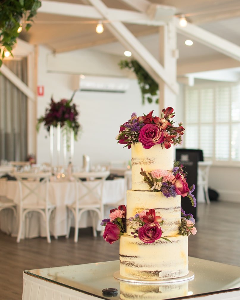 Semi-naked two tier wedding cake with red flowers on display