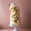 Two tier White wedding cake with white flowers and gold flakes