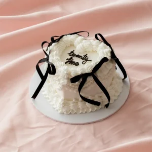 White vintage heart cake with black ribbons added on top.