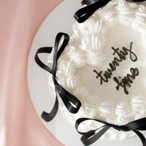 Close up of a white vintage heart cake with black ribbons and writing in black